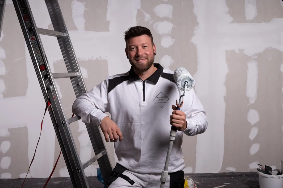 Malermeister Andy mit Farbrolle an der Leiter – Malerarbeiten in Husum