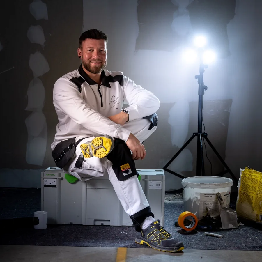 Andy Hansen sitzt lächelnd auf der Baustelle
